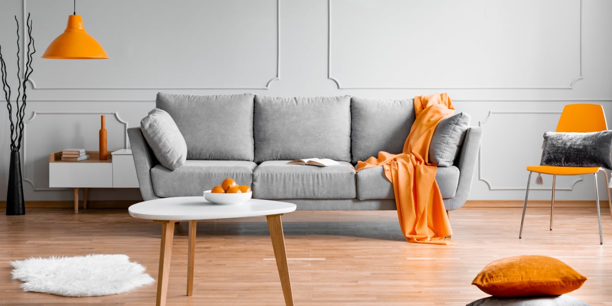 Grey sofa in living room with orange furnishings