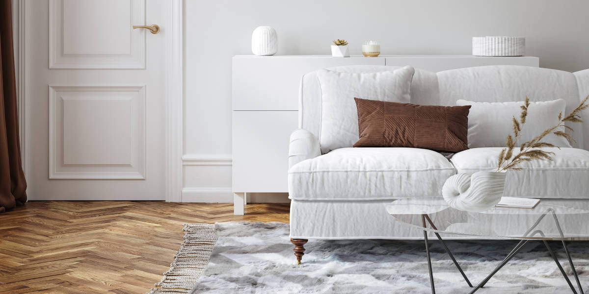 while sofa with wooden floor and grey rug