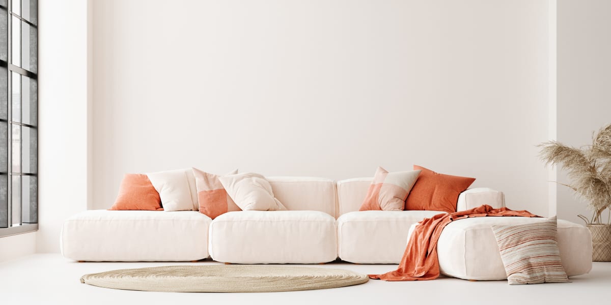 White sofa with orange cushions and orange blanket